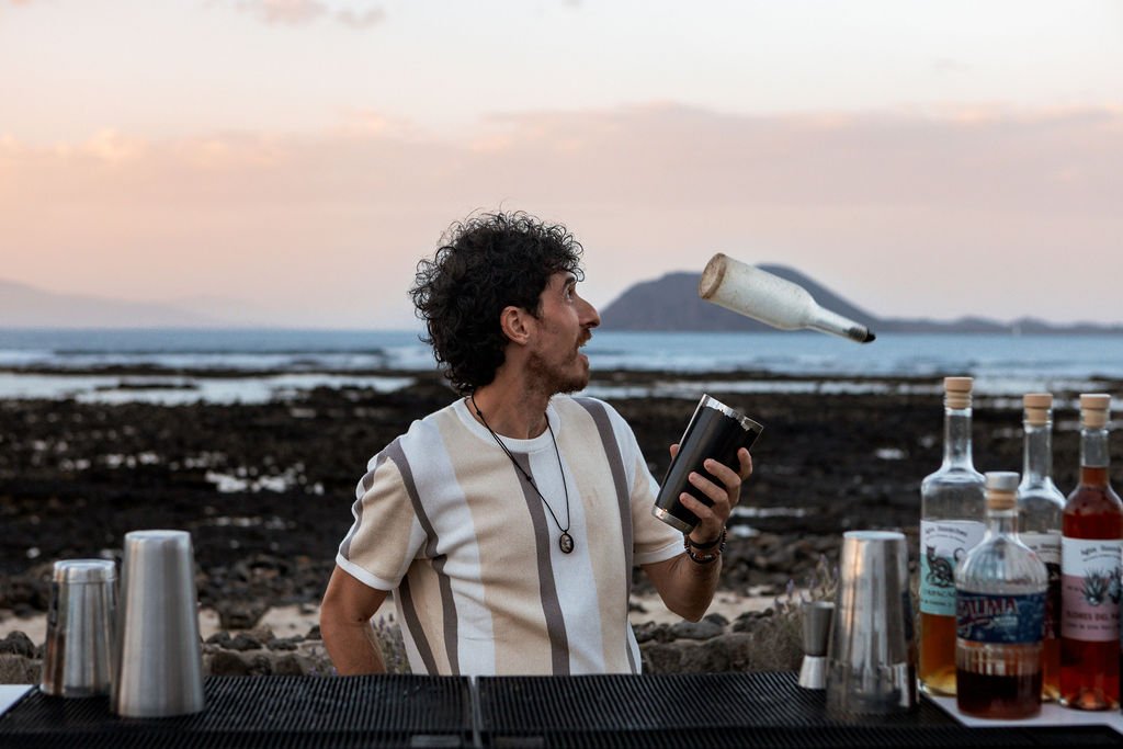 Bartender de InFlow haciendo flair bartending con una botella al atardecer durante un evento en Fuerteventura
